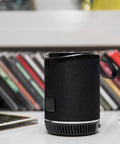 Beat Bluetooth skalrunis ar logo un FM radio, fonā grāmatas, novietots uz galda