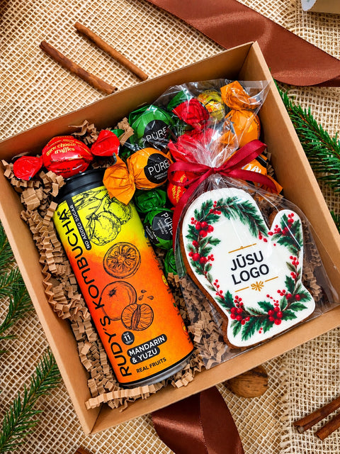 Dāvanu komplekts KRĀSAINAIS atvērtā brūnā kastē ar Rudy’s Kombucha, krāsainām Pūres konfektēm un piparkūku ar personalizētu logo
